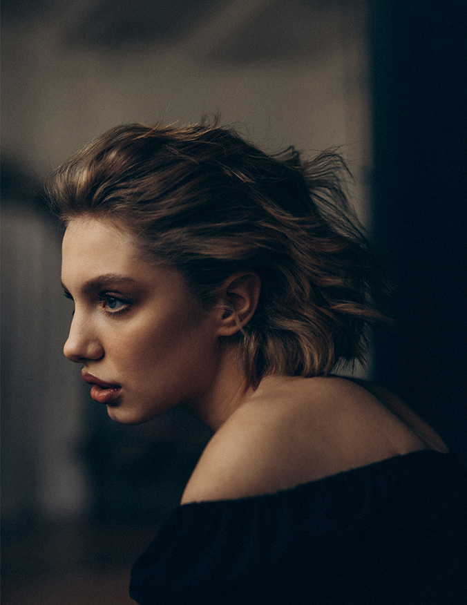 A women from her shoulders up. She is located in the center of the image and is looking to the left. The side of her face shows short dirty blonde hair, slightly pulled back. She has full lips and light eyes and is slightly leaning forward. - Buccal Fat Pad Removal in Los Angeles, CA